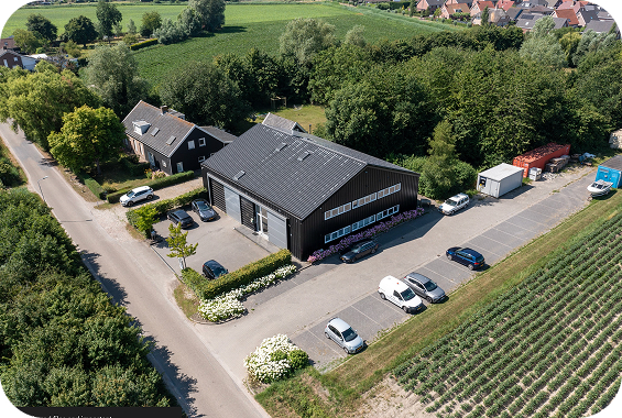 Dronefoto van KustWerk No Guts No Glory kantoor in ’s-Heerenhoek met parkeerplaats en groene omgeving